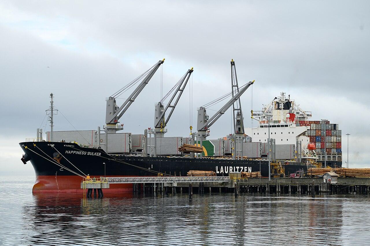 Geared bulk carrier alongside a berth with its cranes raised